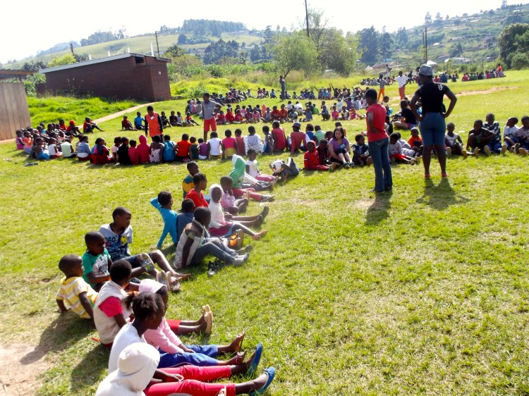 Kids sitting in their four groups to play a ball game